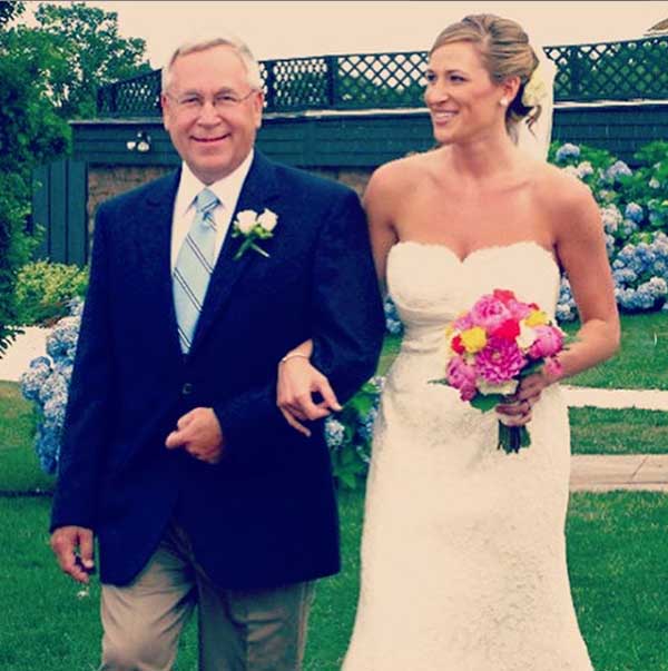 A picture of Sarah walking down an aisle on arm of her father.